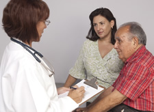 Una profesional de la salud habla con un hombre de edad avanzada y su hija