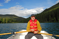 Man relaxing on a rowboat in the middle of a lake